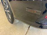 the rear end of a black car with a sticker on it ' s bumper