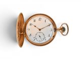 une montre de poche en or sur une surface blanche avec un fond blanc