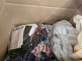 a cardboard box filled with clothing and bags of clothing