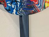 a colorful fan hanging on the wall with a painting on it