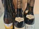 trois bouteilles de vin posées sur une table à côté d'un carton