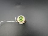 gros plan d'une bague avec une pierre verte entourée de diamants blancs
