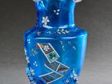 un vase en verre bleu posé sur un socle, sur une surface grise