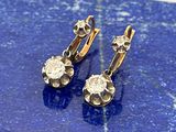 une paire de boucles d'oreilles en diamant posées sur un socle en marbre bleu