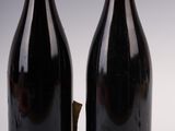 two bottles of wine sitting next to each other on a white surface