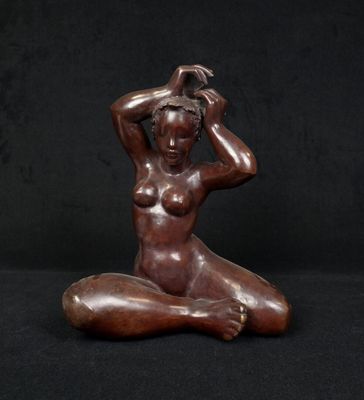 a bronze statue of a woman sitting on a black background