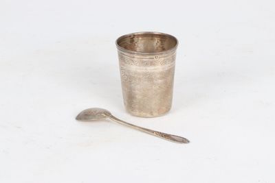 a silver cup with a spoon next to it