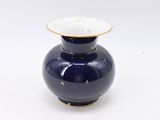 a blue vase with a gold rim sitting on a white surface