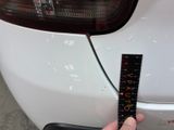 a person holding a ruler in their hand next to a white car