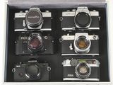 six appareils photo dans un étui, avec un objectif sur le dessus