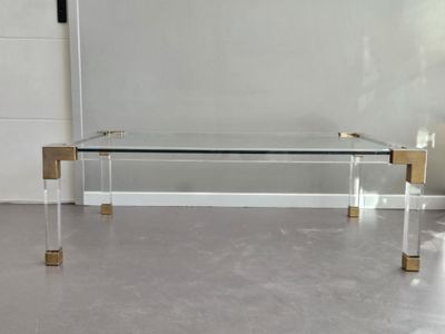 a glass coffee table with gold legs and a glass top