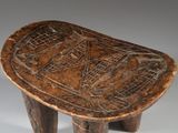 an old wooden stool with a carved design on the top of it