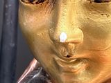 a statue of a woman ' s face with gold paint on it