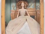 poupée Barbie dans un cadre doré, vêtue d'une robe blanche à bordures dorées