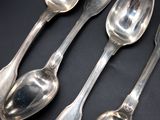 four silver spoons are lined up in a row on a black surface