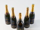 four bottles of champagne are lined up on a white surface