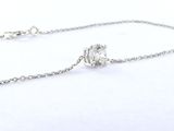 un collier en argent et une bague en argent posés sur une surface blanche
