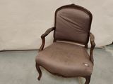 une vieille chaise dont le dossier est recouvert d'un tissu marron et l'assise d'un tissu beige clair