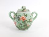 une théière verte décorée d'un oiseau et de fleurs