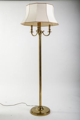 un lampadaire doré surmonté d'un abat-jour blanc