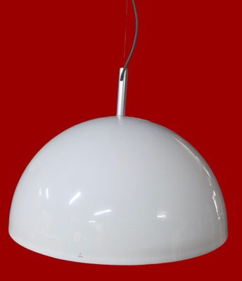 Le grand luminaire blanc est accroché au mur rouge.