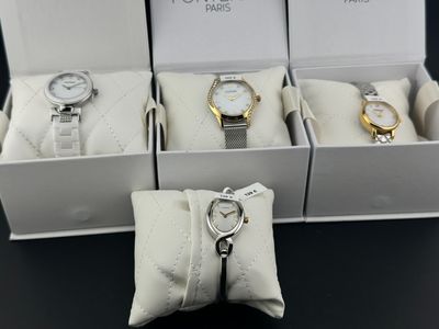 trois montres dans une boîte, avec un porte-clés posé sur une table noire