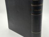 un vieux livre à la couverture noire posé sur une table blanche