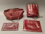 three pieces of red leather purses and a handbag on a table