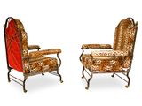 pair of leopard print lounge chairs on casteors with red cushions