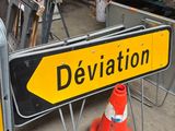 yellow and black street sign sitting on top of a metal stand