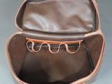 brown leather purse with eyeglasses in it on a gray background