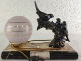 two birds sitting on a tree branch next to a crystal ball