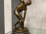 une statue en bronze représentant un homme tenant une batte de baseball