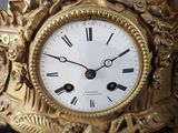 a gold clock with roman numerals on the face