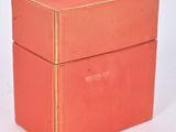 a pink box with a gold lid sitting on a white surface