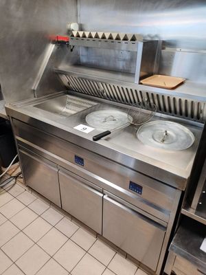 un plan de travail en acier inoxydable sur lequel sont posés trois récipients, dans une cuisine professionnelle