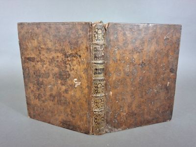 un vieux livre posé sur une table à côté d'un mur blanc