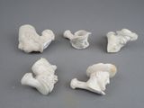 six figurines blanches de formes et de tailles différentes posées sur une surface grise