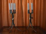 two candles that are sitting on a table in front of a curtain