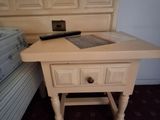 a small table with a laptop on it next to a bed