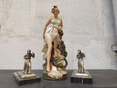 une statue représentant une femme assise sur une table, à côté d'autres statues