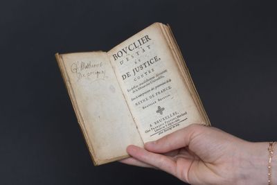 une personne tenant un livre à la main, entouré d'une chaîne