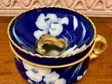 a blue and white bowl with a gold handle on a wooden table