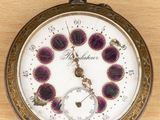 a pocket watch on a wooden table with a clock face