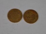 two gold coins sitting side by side on a white surface