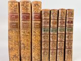 six vieux livres alignés sur une surface blanche