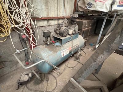 a blue air compressor sitting in a room with a lot of wires
