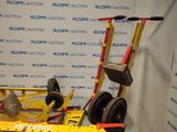 a yellow cart that has wheels on it in front of a wall