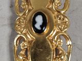 a gold brooch with black and white silhouettes on it