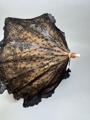 un parapluie en dentelle noire posé sur une surface blanche